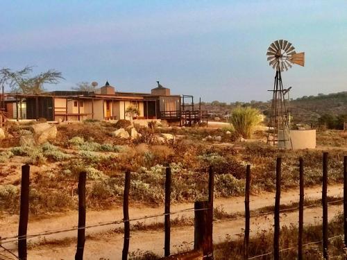 una casa en medio de un campo con un molino de viento en Nuwefonteinskop Lodge en Kotzesrus