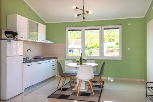 a kitchen with green walls and a table and chairs at KAIROS in Bilice