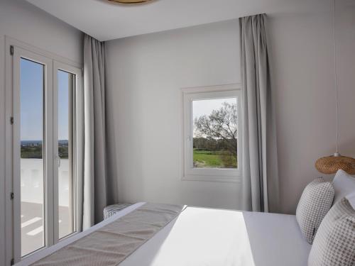 a bedroom with a white bed and a window at Maestro Villas Naxos in Naxos Chora