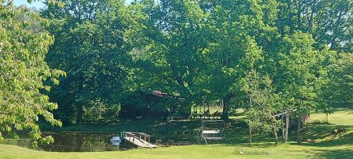 un parque con un estanque, árboles y un puente en Pirts,kubls,,Saknēs,,, en Talsi