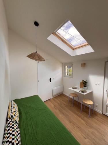 une chambre avec un lit vert et une lucarne dans l'établissement Charmant studio avec terrasse 15m2 fraîchement rénové, à Perros-Guirec