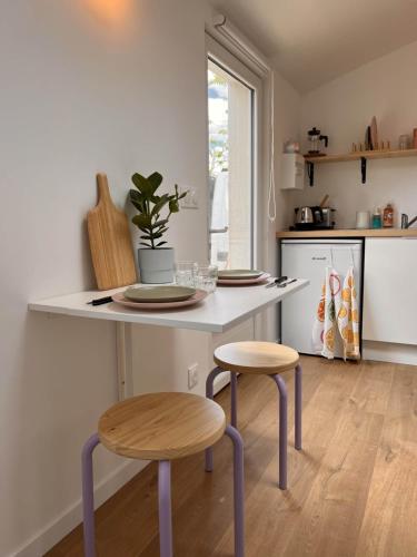 une cuisine avec une table avec deux tabourets et un comptoir dans l'établissement Charmant studio avec terrasse 15m2 fraîchement rénové, à Perros-Guirec