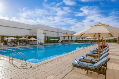 a pool at a hotel with chairs and an umbrella at Four Points by Sheraton Al Ain in Al Ain