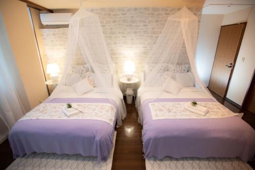 two beds in a room with white linens at White House in Uruma