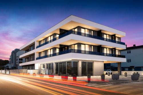 a large white building with a sunset in the background at Fly Apartments Medulin - 50m from the Beach - NEW 2024 in Medulin