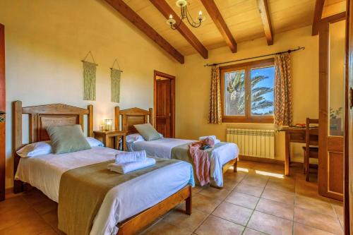 1 dormitorio con 2 camas, escritorio y ventana en Rustica Talaia Vella mit Pool und Wifi, en Cala Santanyi