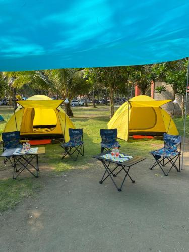 eine Gruppe von Zelten und Stühlen unter einem blauen Baldachin in der Unterkunft Sewa Tenda Pantai Madasari in Madasari