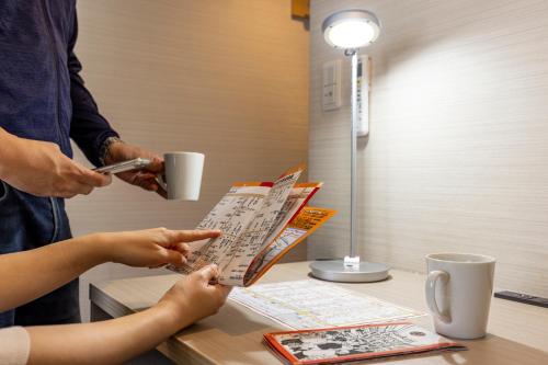 una persona sentada en una mesa leyendo un periódico en Tokyu Stay Tsukiji - Tokyo Ginza Area, en Tokio