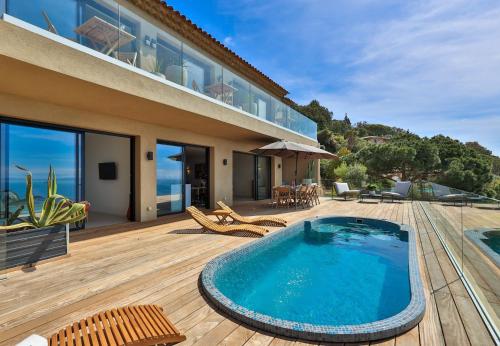 une maison avec une piscine sur une terrasse en bois dans l'établissement Villa Nest, à Rayol-Canadel-sur-Mer