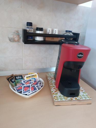a red coffee maker sitting on a counter next to a plate at La veranda del Melograno - Pisticci in Pisticci