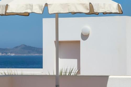 a white house with an umbrella and the ocean at Residence Scirocco e Tramontana in Favignana