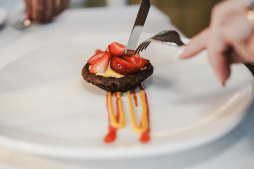 a person eating a dessert with strawberries on a plate at Hotel Bellavista in Cavalese