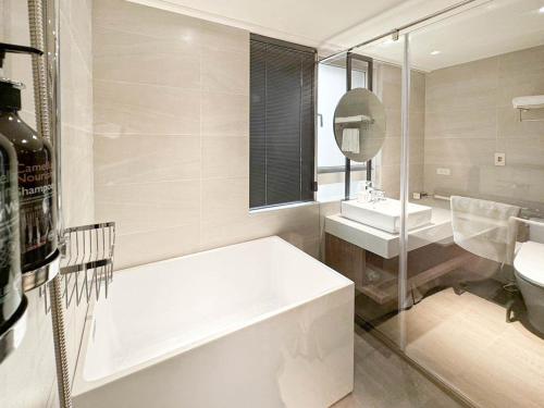 een witte badkamer met een bad en een wastafel bij Royal Rose Hotel Zhongshan in Taipei