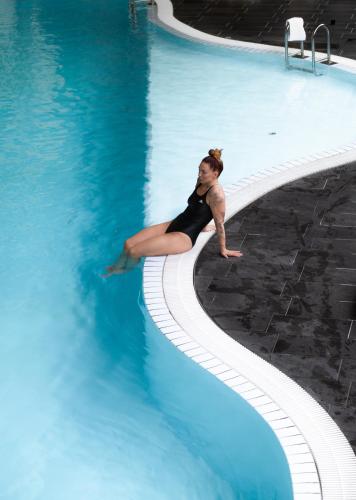 a woman sitting on the edge of a swimming pool at Storhogna Högfjällshotell & Spa in Storhågna