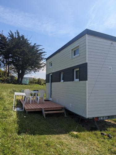 une petite maison avec une terrasse et deux chaises dans l'établissement Tiny House proche de la plage sans draps ni serviettes, à Plévenon