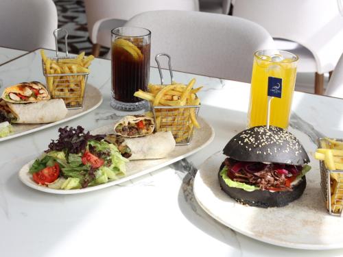 a table with three plates of food and a sandwich and french fries at Vira Otel Suites in Sinop