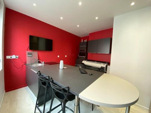 een keuken met een witte tafel en een rode muur bij Chambre Archi in Écourt-Saint-Quentin