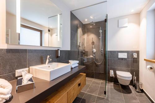 a bathroom with a sink and a toilet and a shower at Bergresort Zugspitze Ehrwald by ALPS RESORTS in Ehrwald