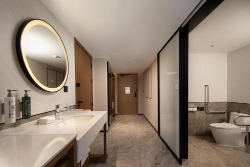 a bathroom with a sink and a toilet and a mirror at Hilton Garden Inn Beijing West Railway Station in Beijing
