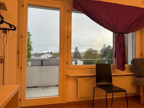 a room with a window with a chair in front of it at Room with balcony in Ober Urdorf