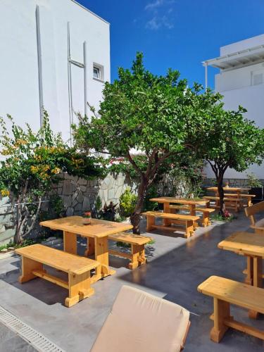 Una hilera de mesas de picnic de madera y árboles frente a un edificio. en Oceanis Resort, en Parikia