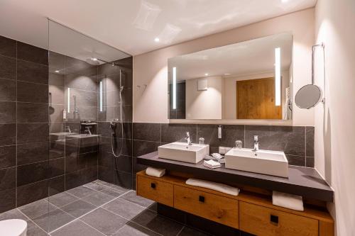 a bathroom with two sinks and a shower at Bergresort Zugspitze Ehrwald by ALPS RESORTS in Ehrwald