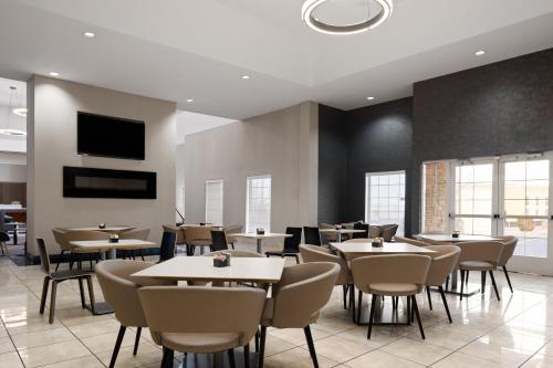 a restaurant with tables and chairs and a tv at Holiday Inn & Suites Albuquerque Airport by IHG in Albuquerque