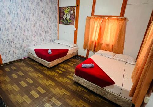twee bedden in een kamer met houten vloeren bij MUKUT CORAL CHALET in Tioman Island