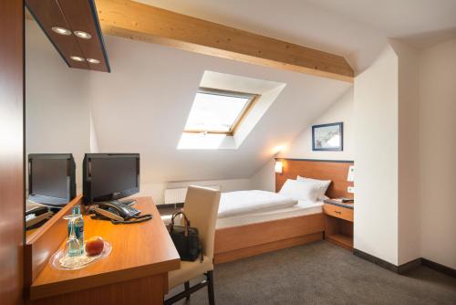 een slaapkamer met een bed en een bureau met een computer bij Hotel am Wald in Monheim