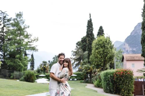 a bride and groom pose for a picture in front of a garden at Lido Palace - The Leading Hotels of the World in Riva del Garda