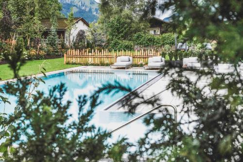 a swimming pool in a yard with two lounge chairs at Bergresort Zugspitze Ehrwald by ALPS RESORTS in Ehrwald