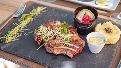 a plate of food with meat and vegetables on a table at Hotel Les Tourelles in Sainte-Maxime