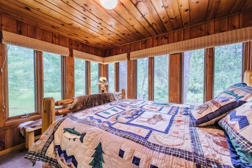 - une chambre avec un lit dans une pièce dotée de fenêtres dans l'établissement Cozy Riverside Getaway Pine Bend 4BDR Cottage 5589, à Grayling