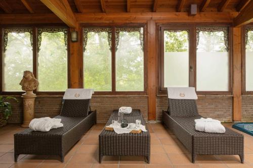 un porche con 2 sillas de mimbre y una mesa en Hotel & Spa Etxegana, en Zeanuri