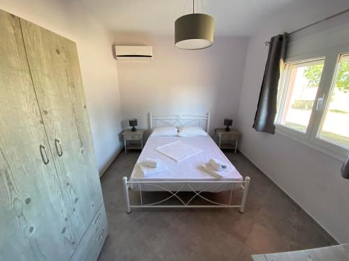 a bedroom with a white bed and a window at Pefki Apartment 8 in Artemísion