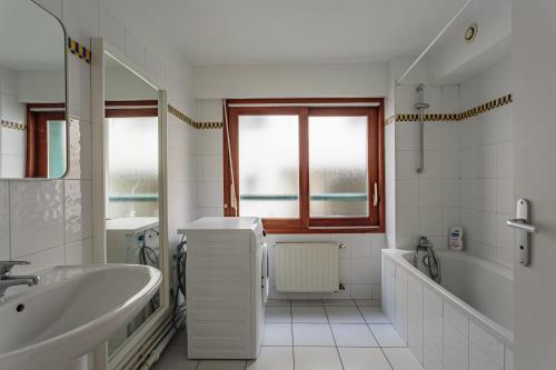 une salle de bain blanche avec une baignoire et un lavabo dans l'établissement Appartement moderne en plein centre ville, à Biarritz