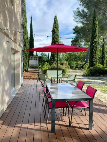 - une table et des chaises avec un parasol rouge sur la terrasse dans l'établissement Au calme dans la campagne Aixoise, entouré de cyprès, à Aix-en-Provence