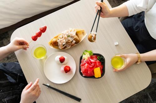 two people sitting at a table with food and drinks at Tokyu Stay Tsukiji - Tokyo Ginza Area in Tokyo
