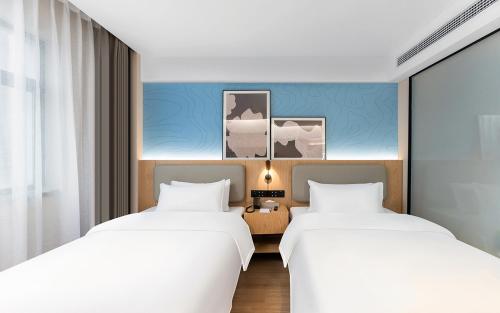 two beds in a hotel room with white sheets at Country Inn & Suite by Radisson, Nanchang Tengwangge Wanshou Palace Subway Station in Nanchang