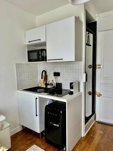 une petite cuisine avec des armoires blanches et un évier dans l'établissement Séjour parisien Suite Bastille, à Paris