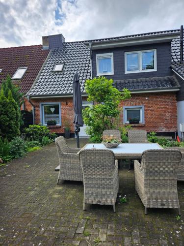 a table with chairs and an umbrella in front of a house at Ferienwohnung 2 Am Park in Divitz