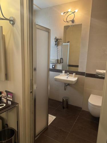 a bathroom with a sink and a toilet and a mirror at Hotel Vivaldi in Puteaux