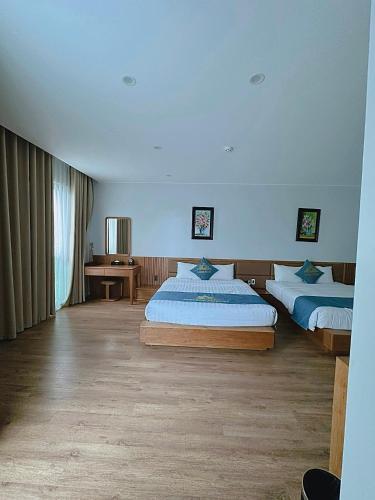 a bedroom with two beds and a table and a window at Queen Hotel Hoàng Gia in Thái Nguyên
