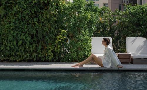a woman sitting on a chair next to a pool at The Singapore EDITION in Singapore