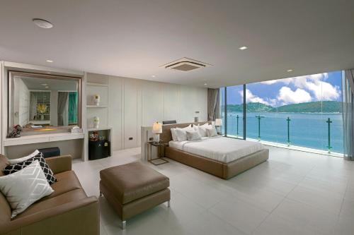 a bedroom with a bed and a couch and a large window at Villa W Luxury in Nai Harn Beach