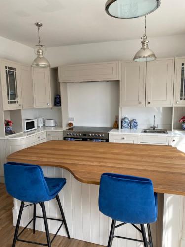 a kitchen with two blue chairs and a wooden counter at Fitzgeralds - Ballybunion - Sleeps 34 in Ballybunion