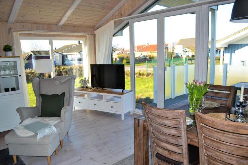 sala de estar con TV, mesa y sillas en Ferienhaus "Deichglück" direkt an der Nordsee 2023 saniert, en Wesselburenerkoog