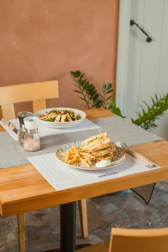 a table with two plates of food and a plate of french fries at Dominoes Corfu in Ýpsos
