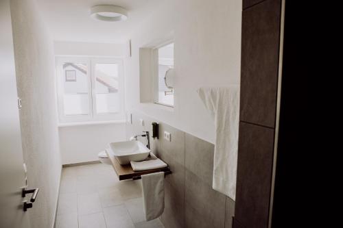 a white bathroom with a sink and a window at Zur Pfanne – Studio in Biberach an der Riß