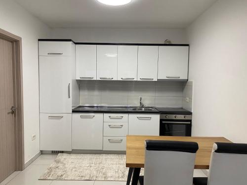 a kitchen with white cabinets and a wooden table at City Center 2bedroom in Ferizaj